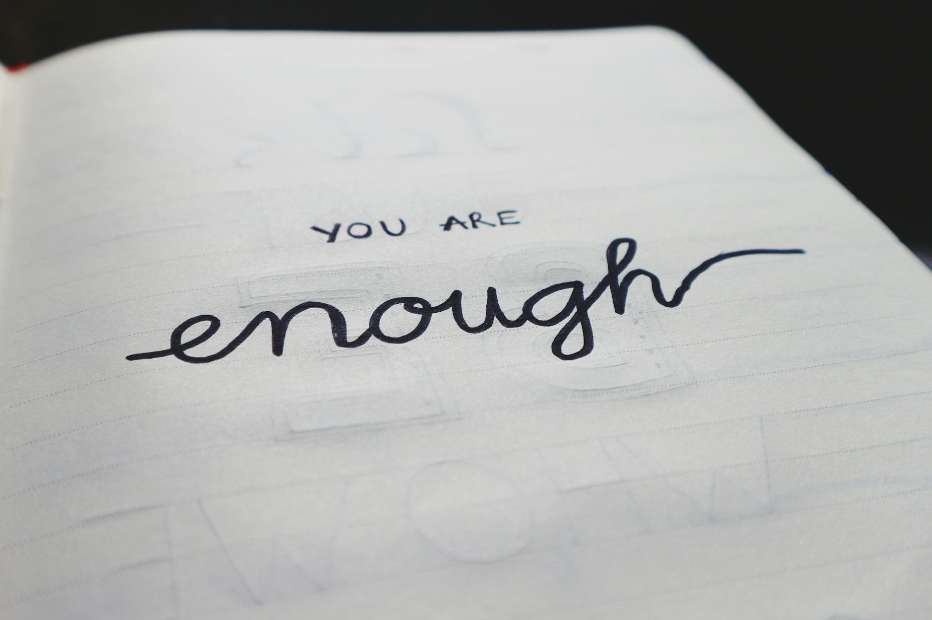 Zbliżenie notesu z ręcznie napisanym hasłem You are enough