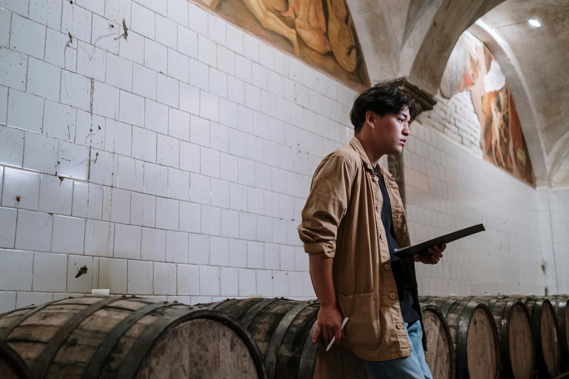 Specjalista sprawdza drewniane beczki w browarze z listą kontrolną