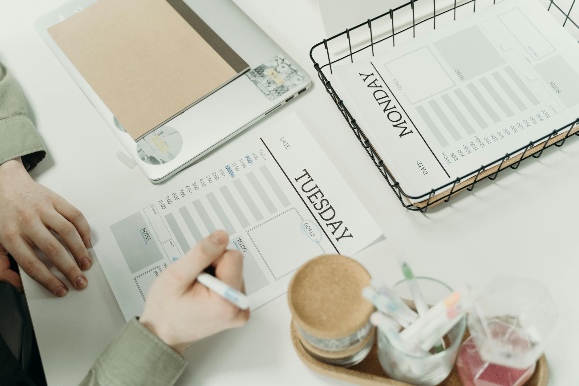 Właściciel firmy planuje tydzień przy biurku z papierowym planerem