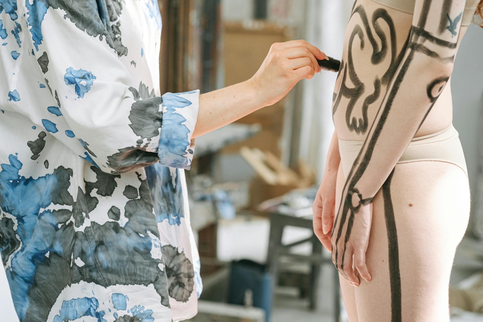 Artysta maluje ciało modelki kolorowymi wzorami w studiu