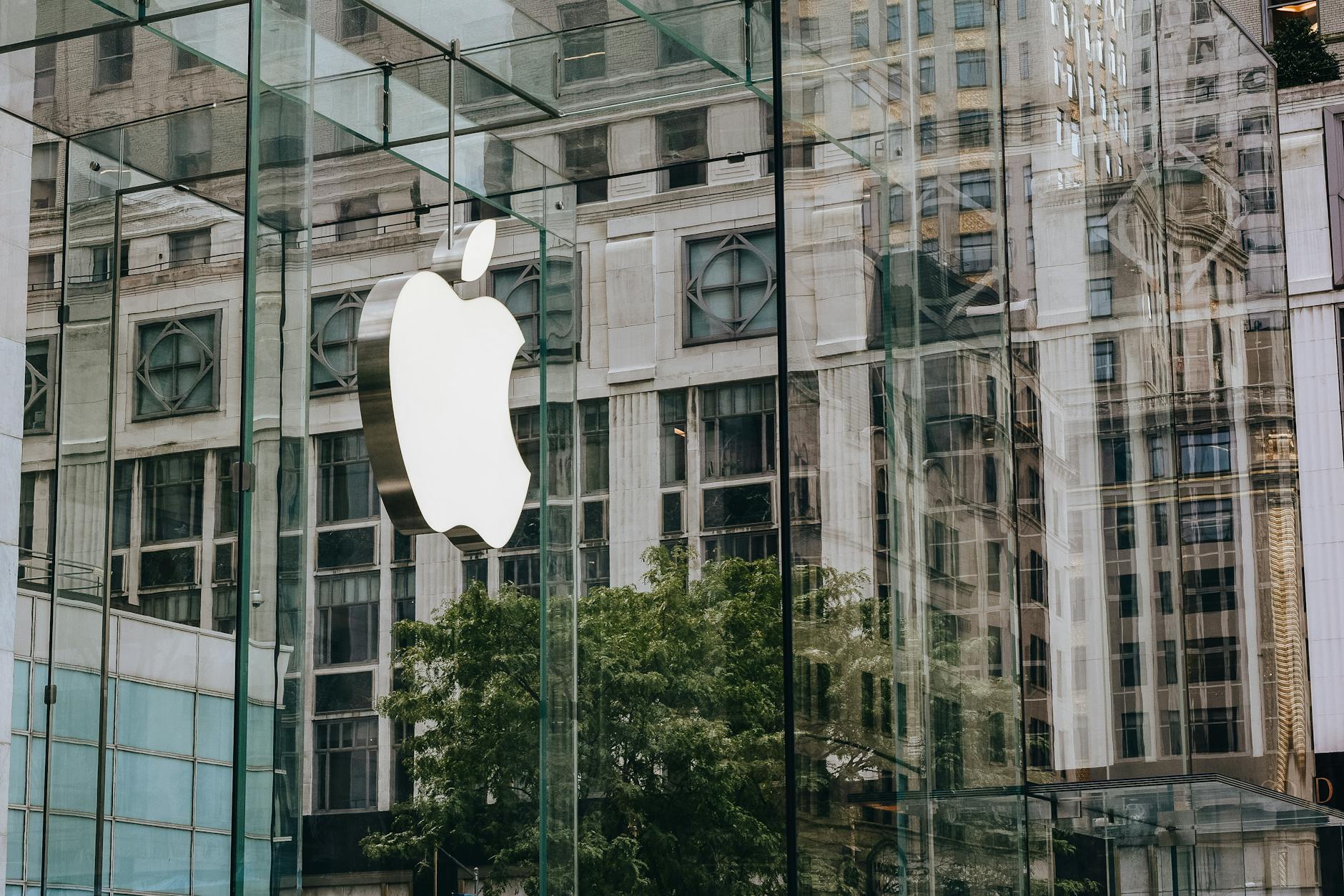 Logo Apple na szklanej fasadzie biurowca w nowoczesnym otoczeniu miejskim