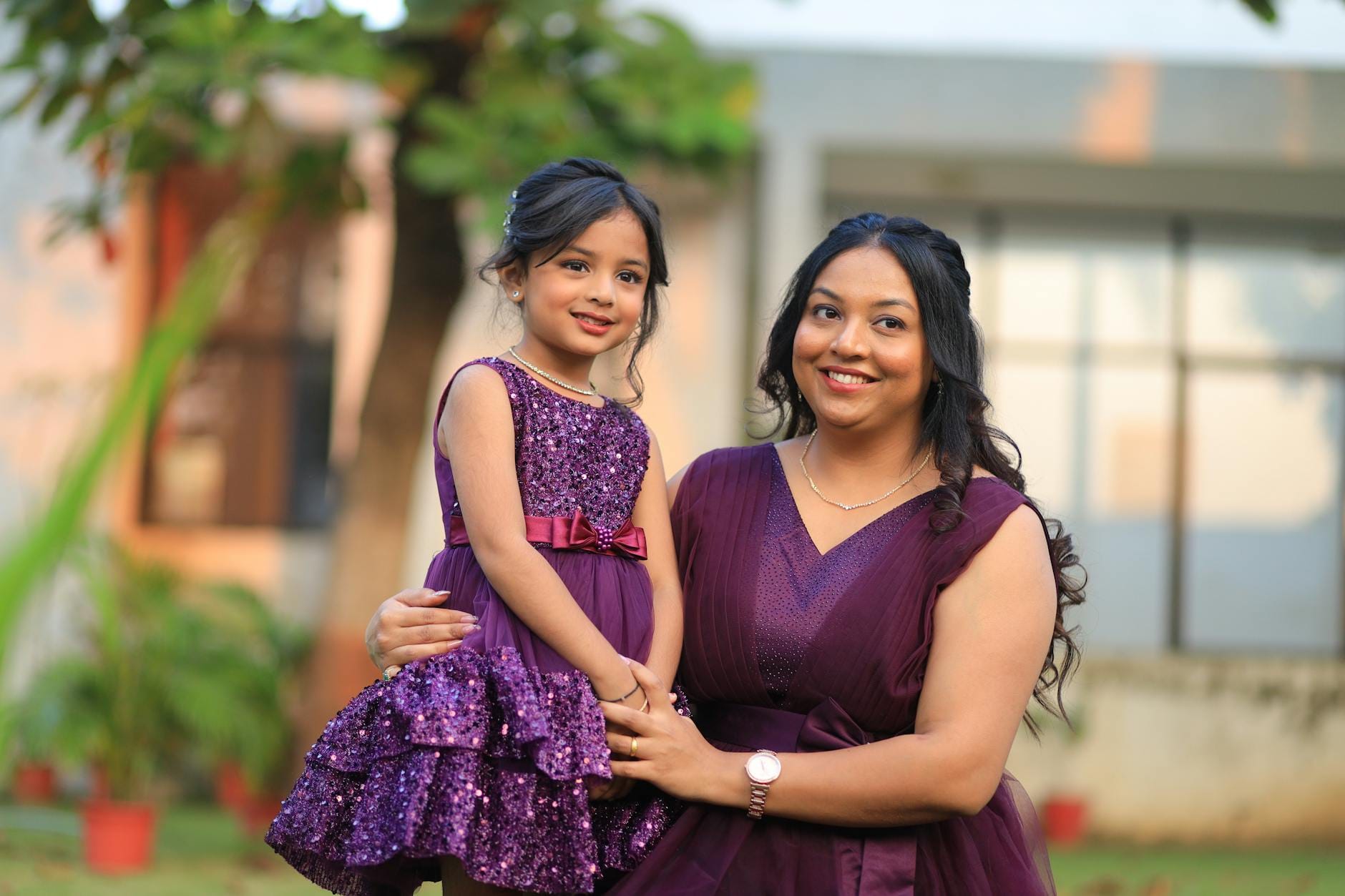 Mama i córka w dopasowanych fioletowych sukienkach na dworze