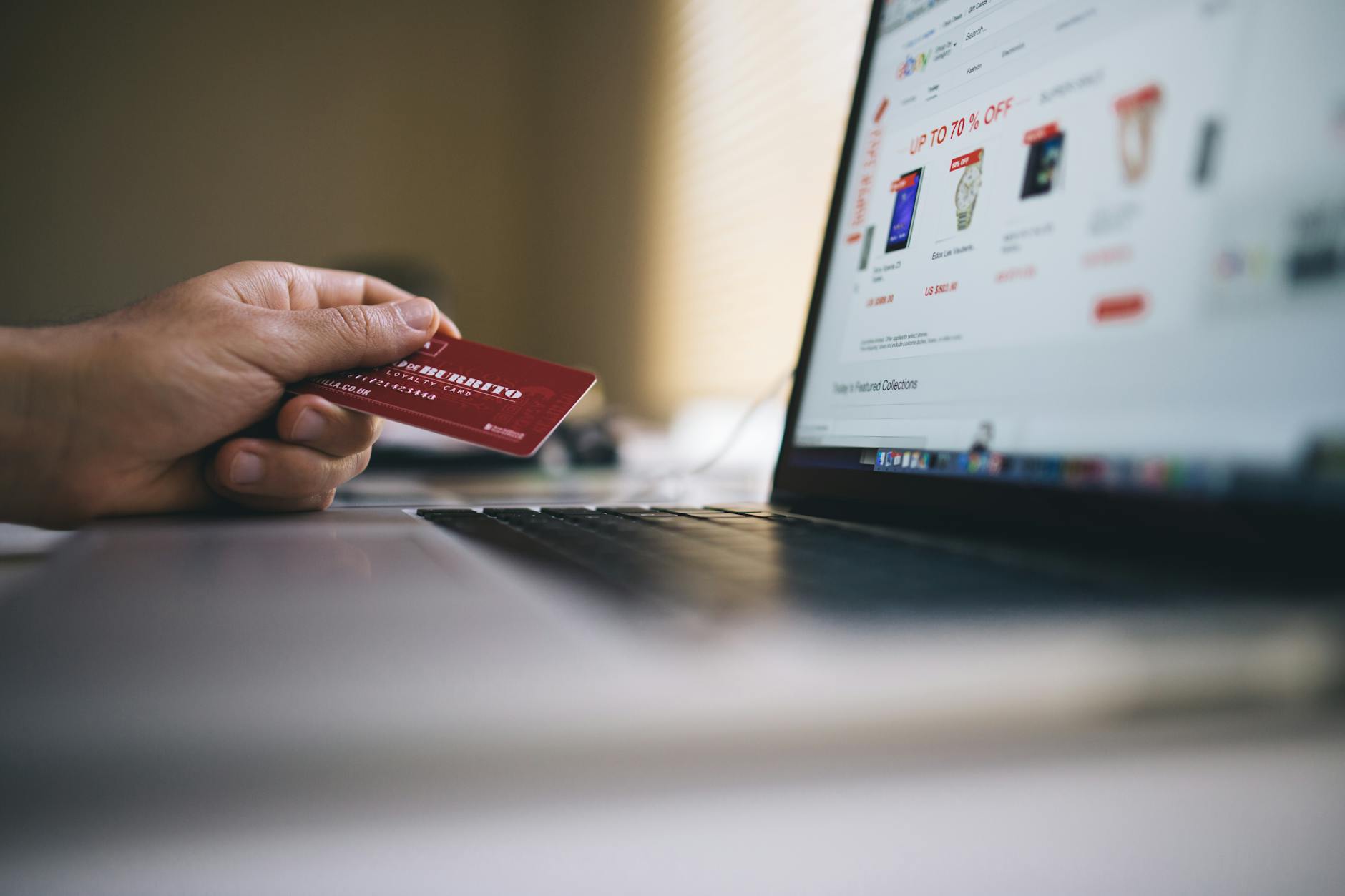 Osoba płaci kartą za zakupy online na laptopie