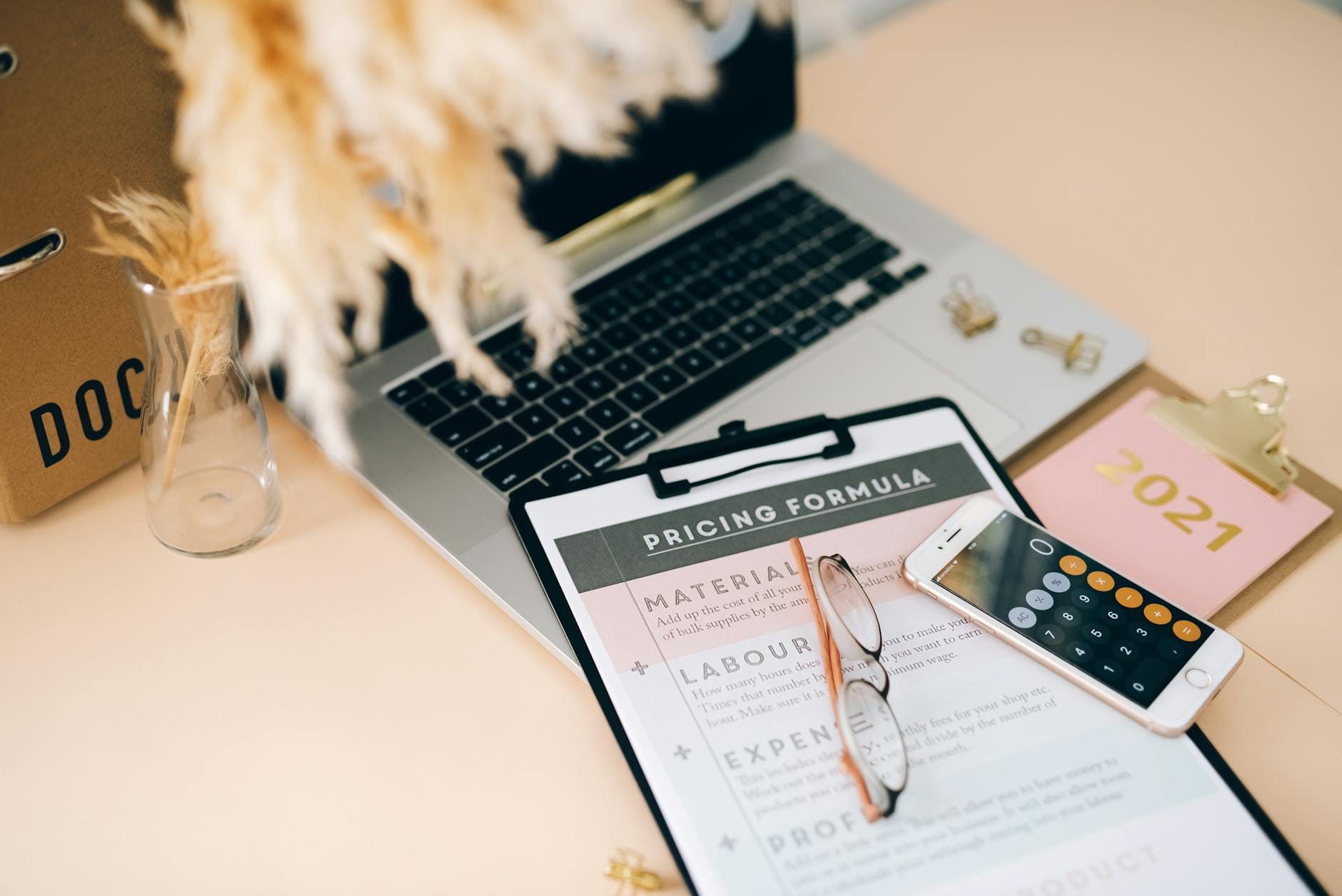 Biurko z laptopem, kalkulatorem w telefonie i dokumentem z formułą wyceny