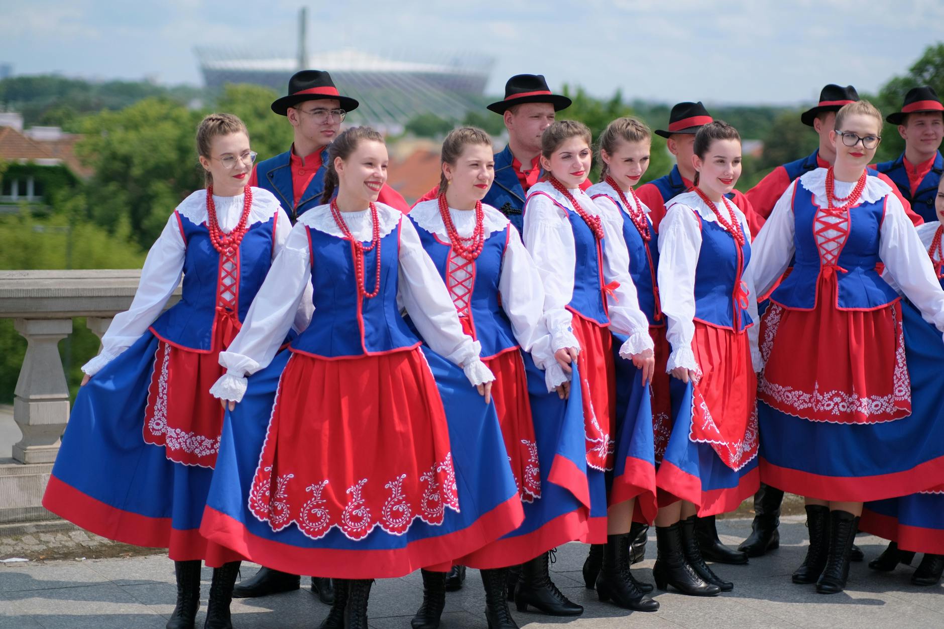 Grupa osób w polskich strojach ludowych pozuje na dworze