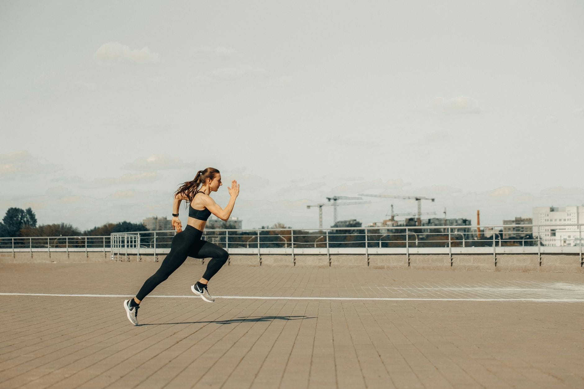 Kobieta w stroju sportowym biegnie sprintem po dachu budynku