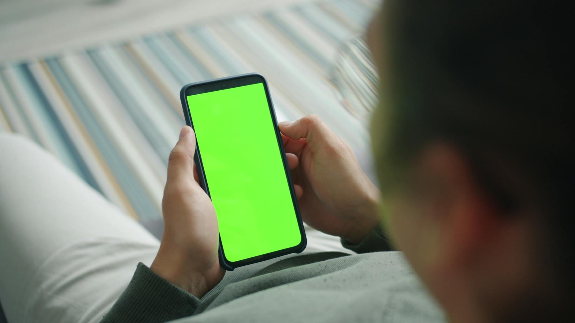 Osoba trzyma smartfon z zielonym ekranem podczas pracy nad treściami