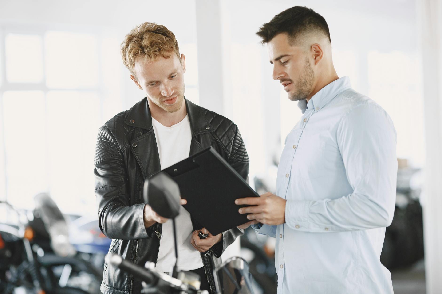 Sprzedawca i klient przy biurku omawiający umowę zakupu motocykla