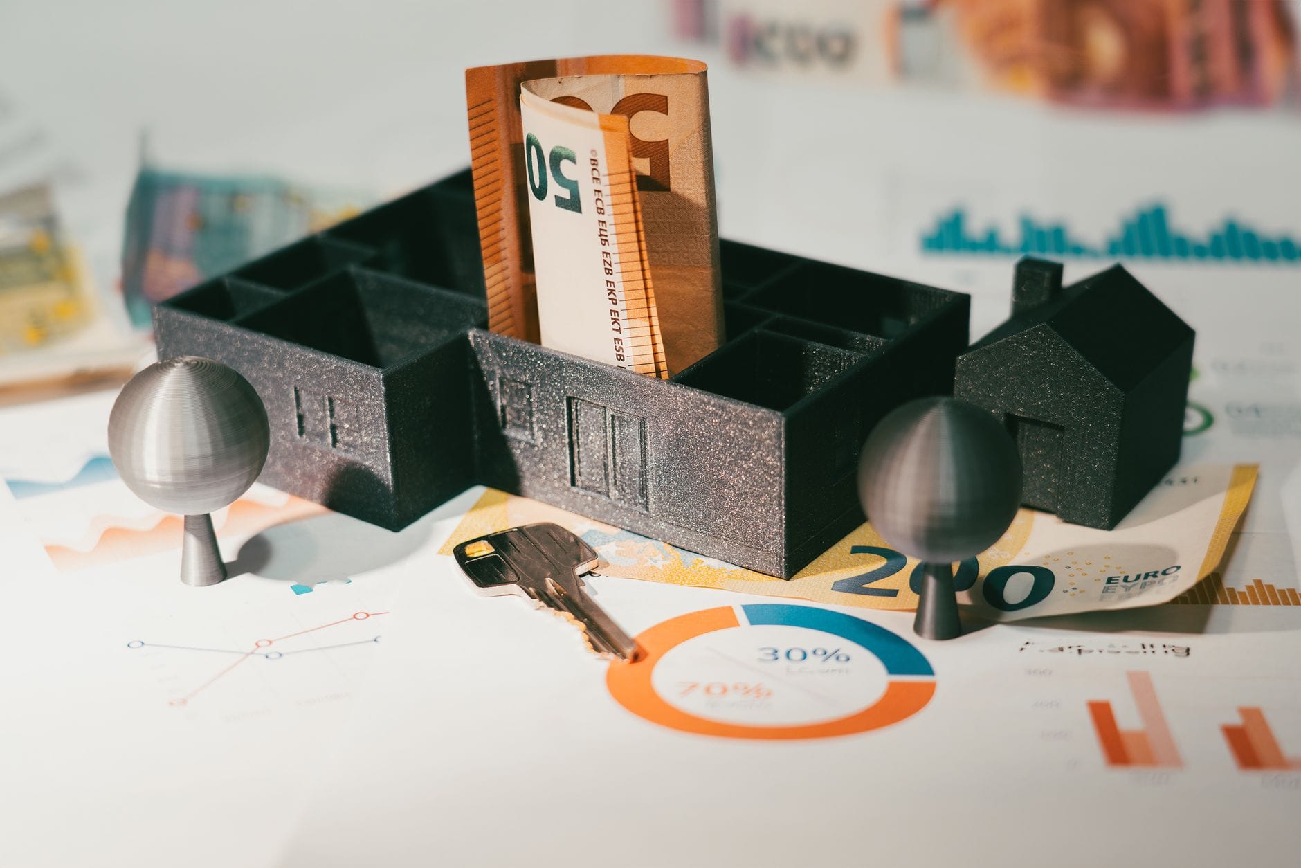 Banknoty euro, makieta domu i wykresy finansowe na biurku