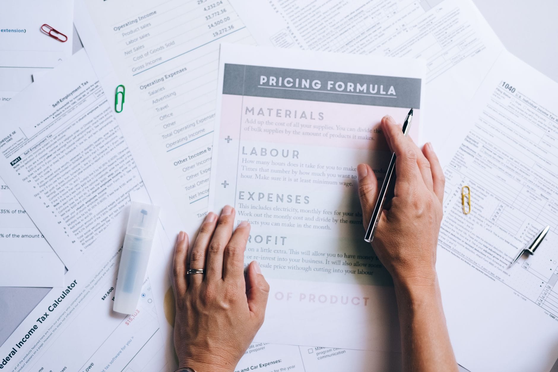 Dłonie układają dokumenty z formułami cen na biurku w biurze