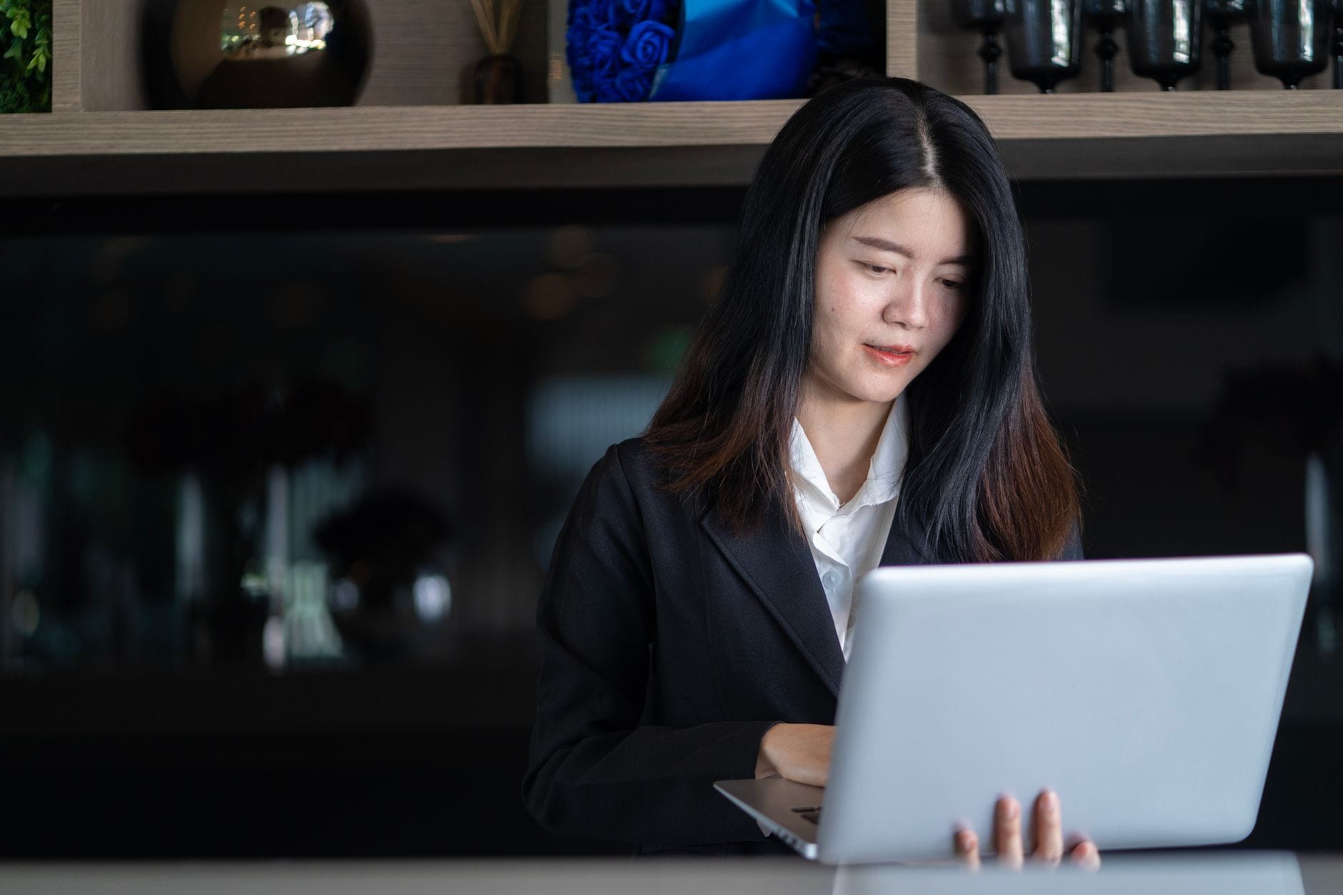 Młoda Azjatka freelancerka pracuje przy laptopie w nowoczesnym biurze
