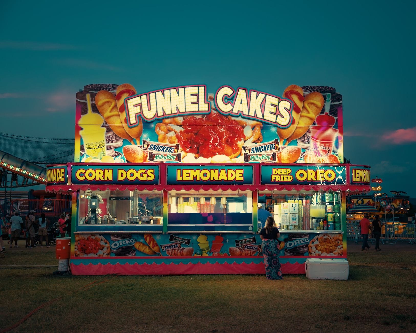 Kolorowe stoisko z funnel cake oświetlające wieczorne wesołe miasteczko