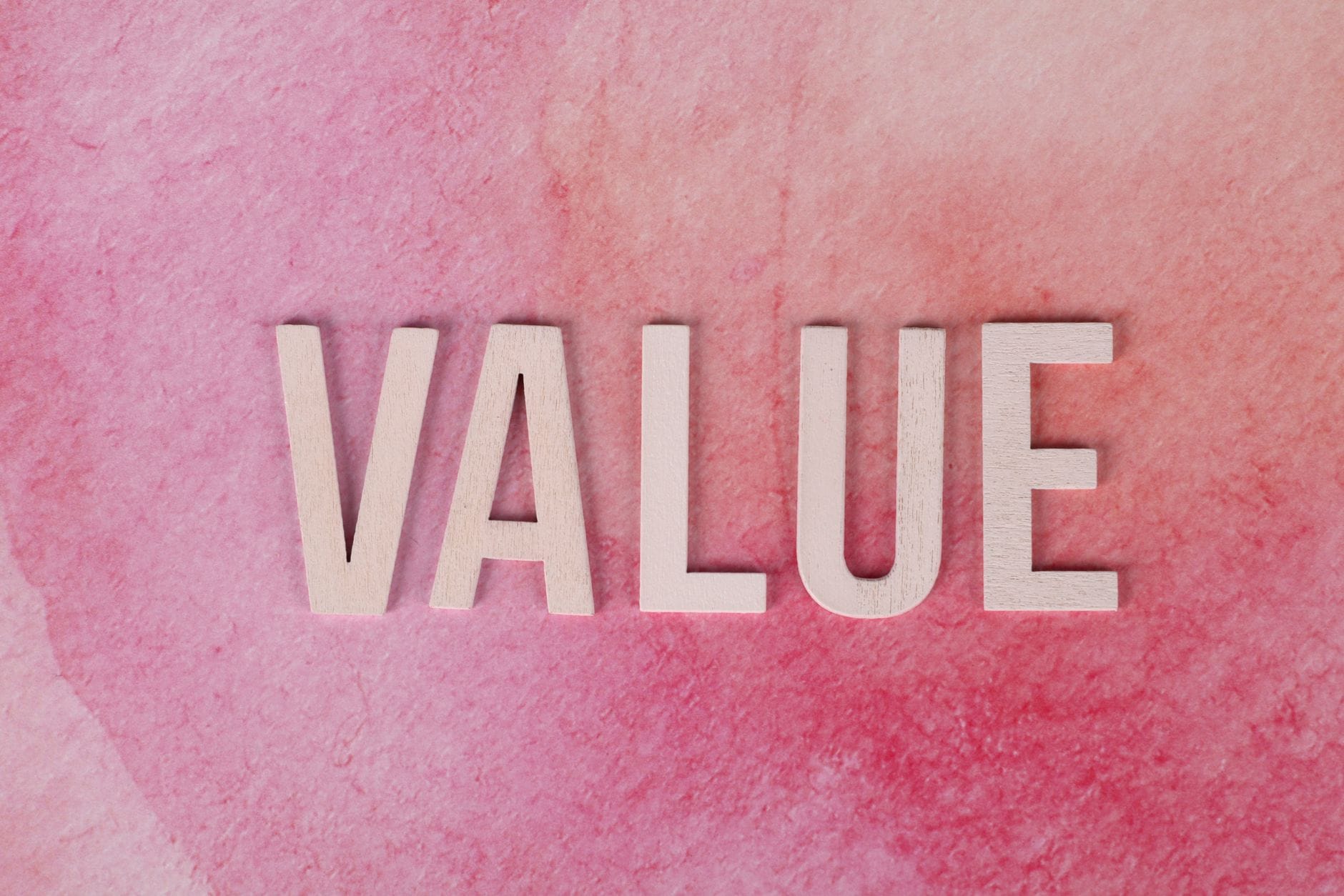 Napis VALUE dużymi literami na różowym, fakturowanym tle