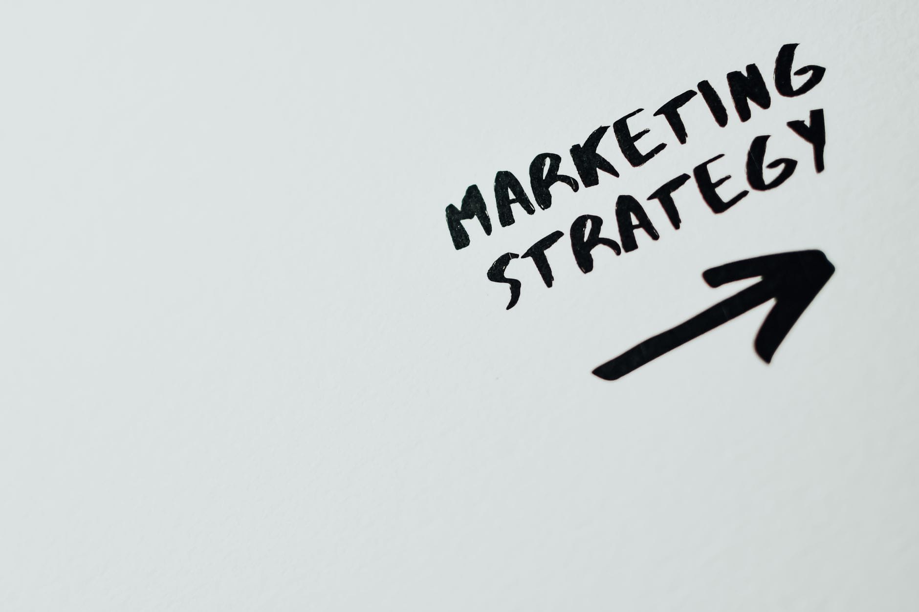 Zbliżenie ręcznie napisanego napisu Marketing Strategy z narysowaną strzałką